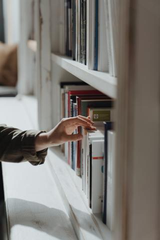 Hand On Book on Shelf